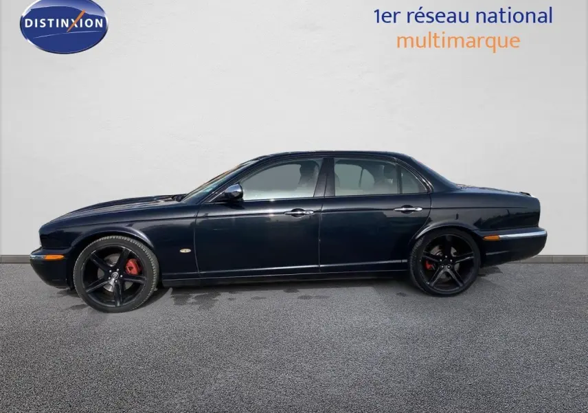 Profil côté gauche d'une Jaguar XJ6 noire de 2006 avec jantes noires et étriers de frein rouges visibles.