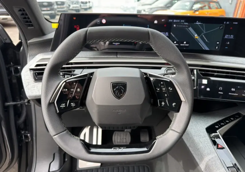 Vue centrée sur le volant cuir perforé GT du Peugeot 3008 Hybrid 145, avec tableau de bord digital et écran tactile.