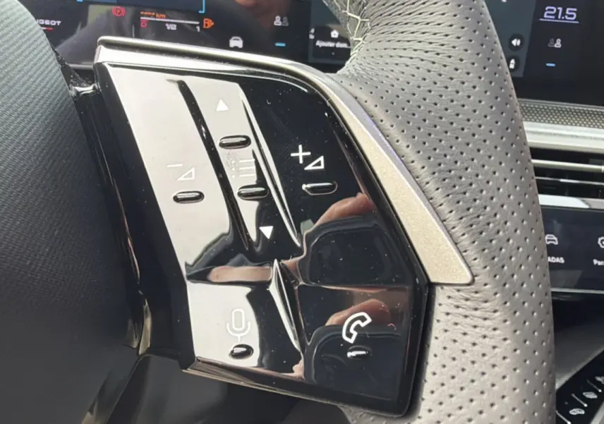 Gros plan sur le volant cuir perforé du Peugeot 3008 Hybrid 145 GT Alcantara avec commandes multifonctions noires brillantes.