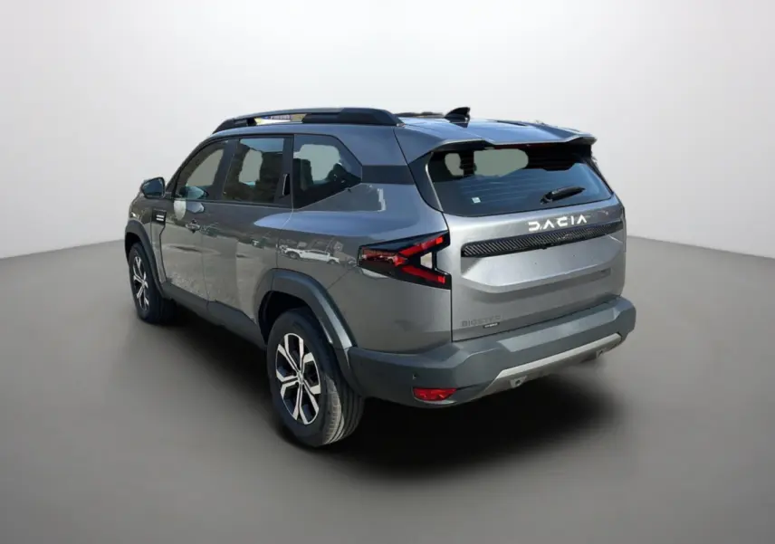 Vue 3/4 arrière droite du Dacia Bigster hybride gris schiste avec barres de toit et jantes alu 17 pouces.