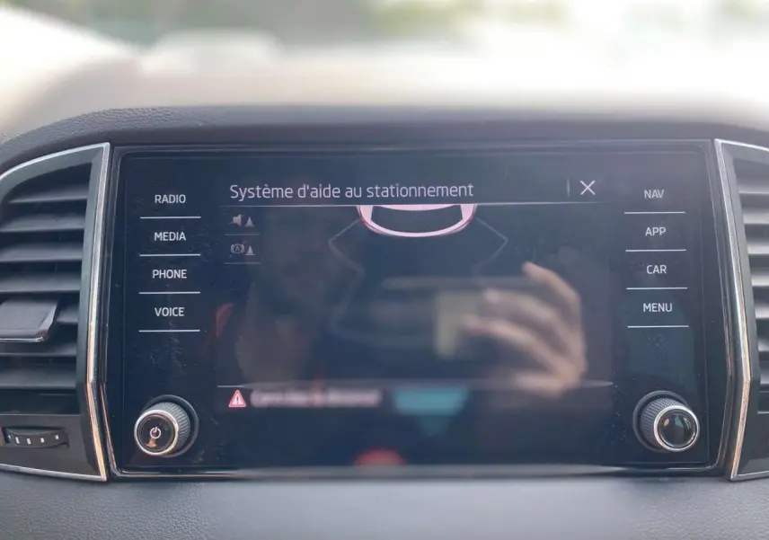 Écran tactile central du tableau de bord du Skoda Karoq 2021, affichant le système d’aide au stationnement.