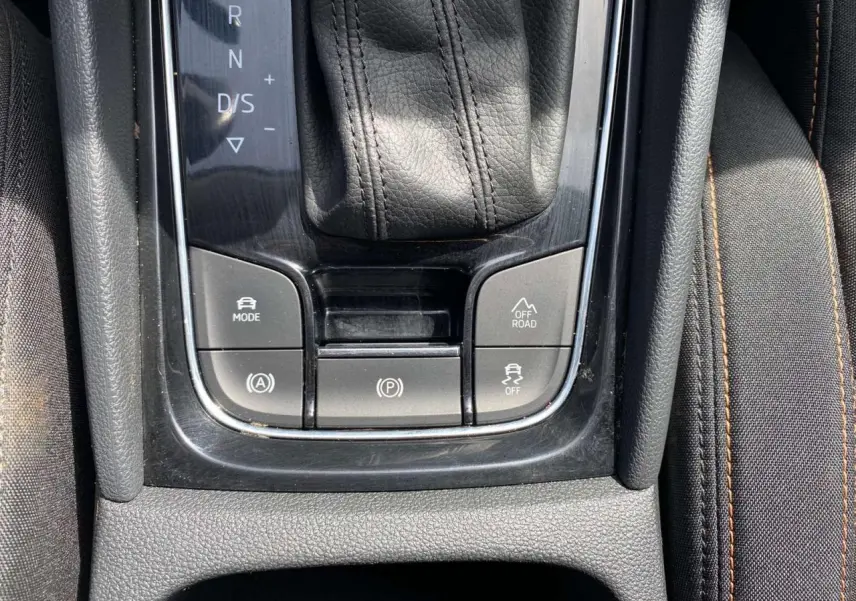 Gros plan sur la console centrale du Skoda Karoq vert foncé 2021, avec levier de vitesse automatique et boutons mode off-road.