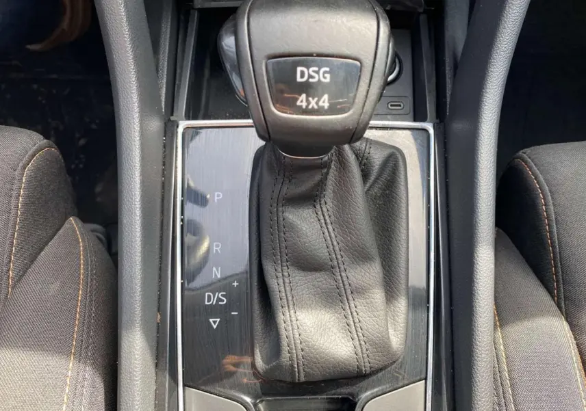 Gros plan sur le levier de vitesses DSG 4x4 noir du Skoda Karoq Scout 2021, entouré de sièges tissu gris foncé.