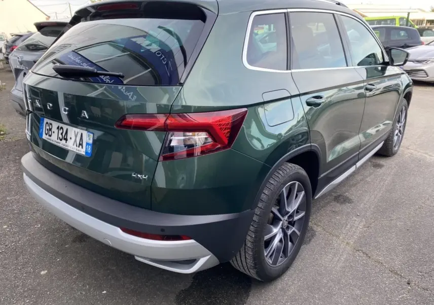 Vue 3/4 arrière droite d’un Skoda Karoq Scout vert foncé avec jantes alliage et badge 4x4 visible.