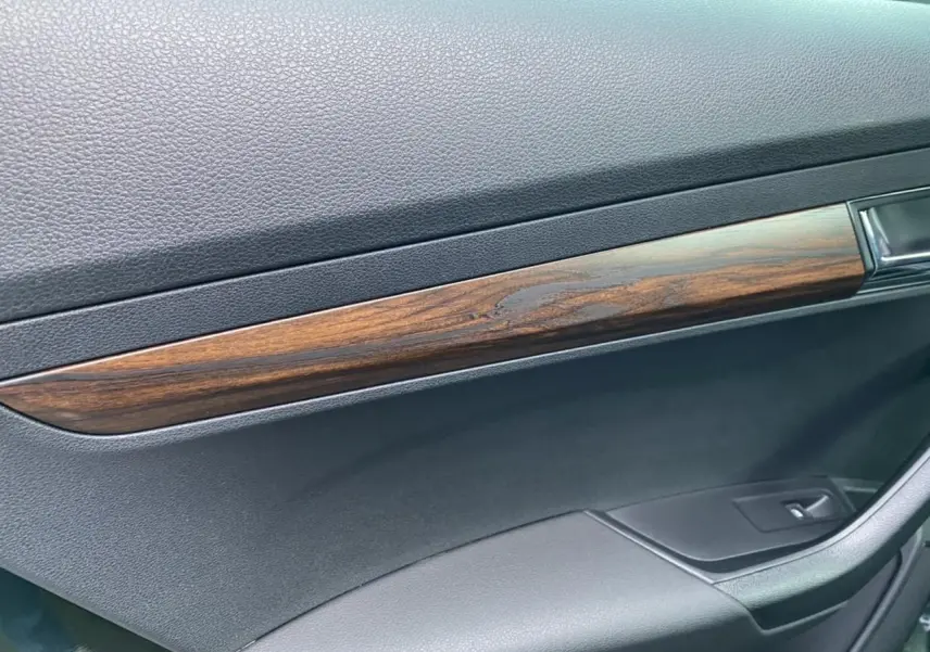 Détail de la garniture intérieure en bois sur la porte côté droit d'un Skoda Karoq Scout 2021 vert foncé.