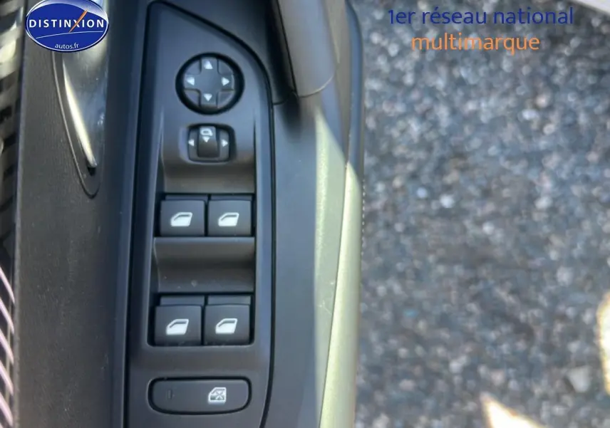 Gros plan sur les commandes de lève-vitres côté conducteur d'une Peugeot 2008 gris Artense, avec bouton de réglage des rétroviseurs.