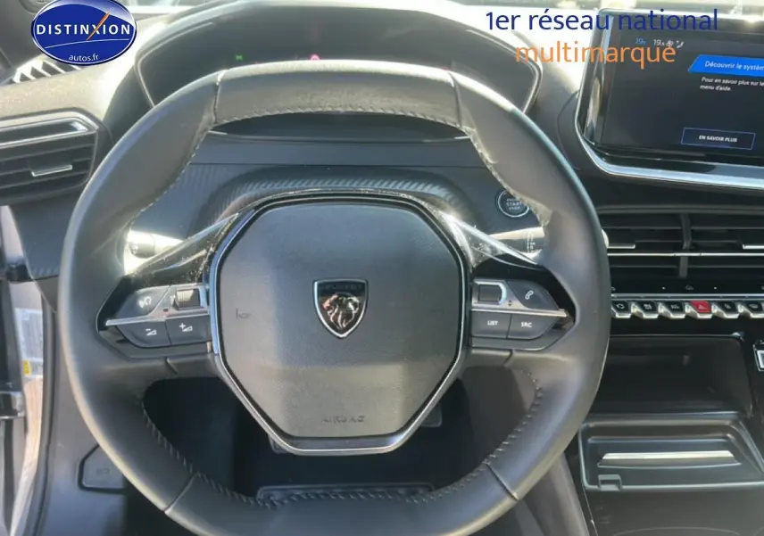 Vue rapprochée du volant multifonction noir de la Peugeot 2008 1.2 100 Allure avec tableau de bord et écran tactile visibles.