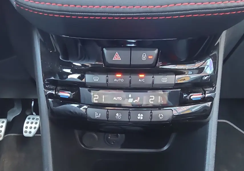 Vue rapprochée de la console centrale noire de la Peugeot 208 GTI 2015, avec climatisation automatique et commandes tactiles.