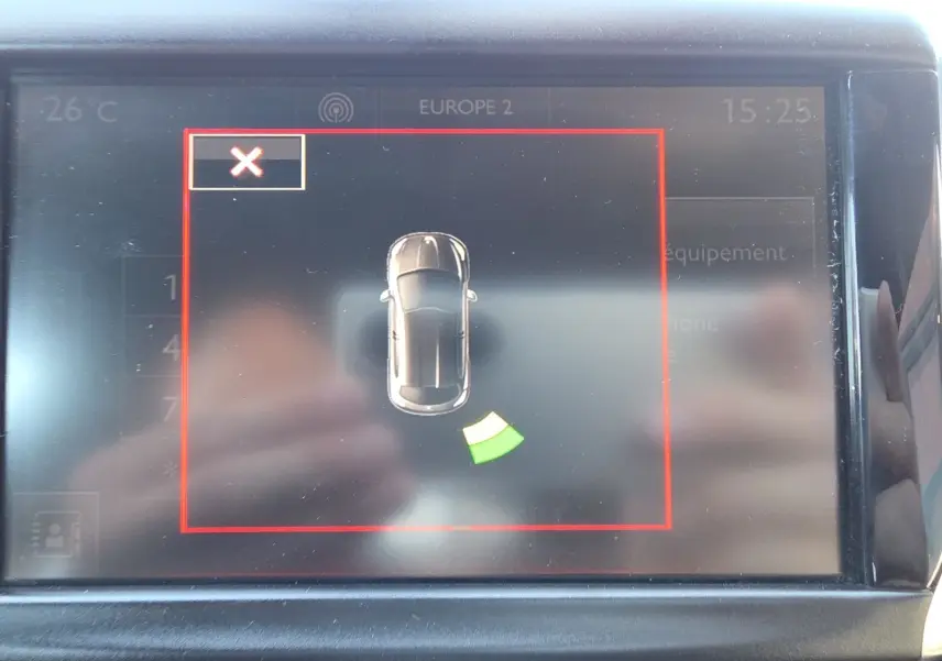Écran central de la Peugeot 208 GTI 2015 montrant l'alerte radar de stationnement arrière avec icône voiture noire vue de dessus.