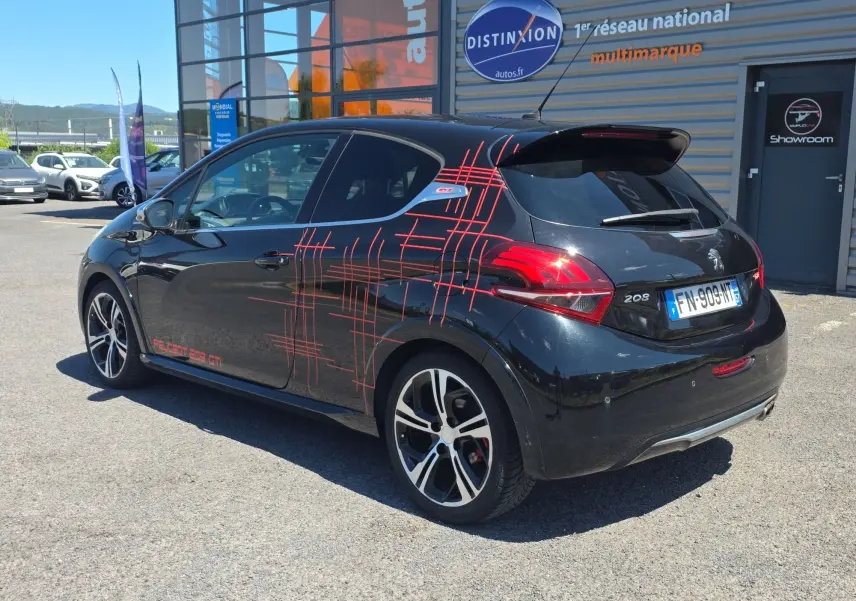 Peugeot 208 GTI noire vue 3/4 arrière droit avec jantes alliage 17” et décorations rouges sportives sur la carrosserie.