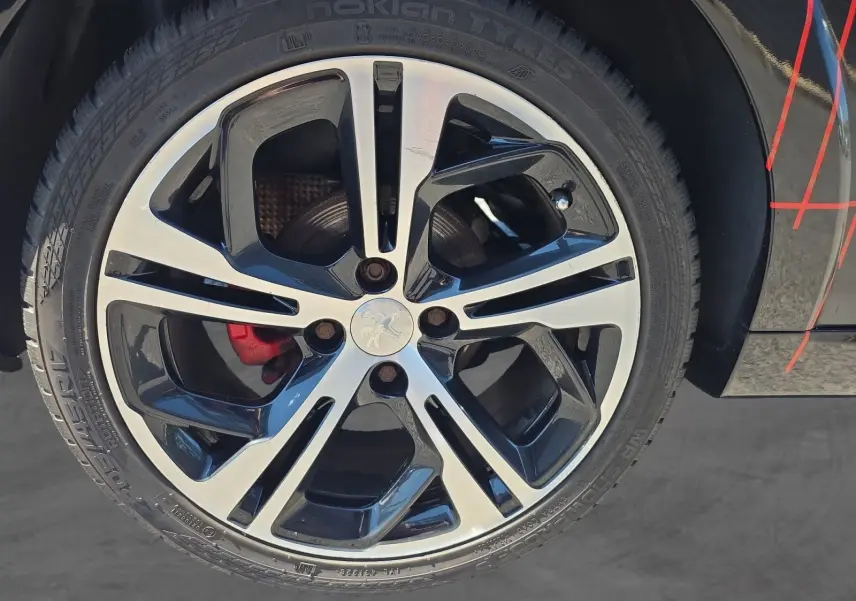 Gros plan sur la jante alliage 17” bicolore noire et argentée de la Peugeot 208 GTI noire avec étrier de frein rouge visible.