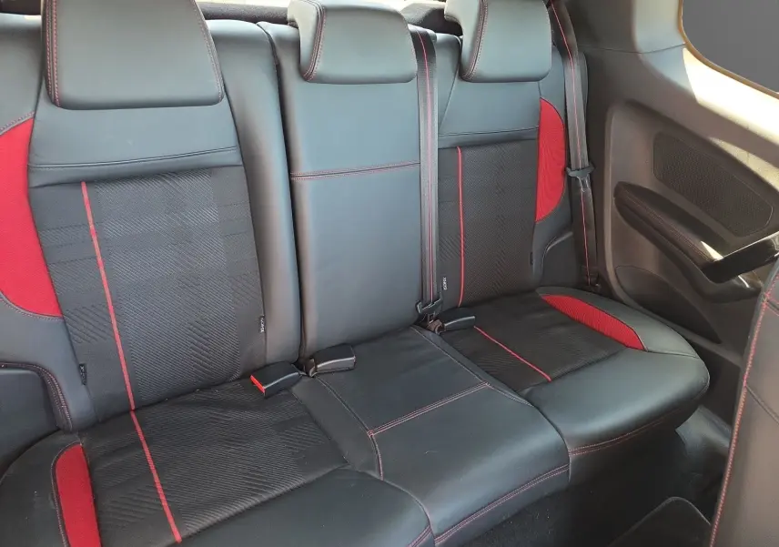 Vue intérieure arrière des sièges cuir et alcantara noirs avec surpiqûres rouges de la Peugeot 208 GTI 2015.