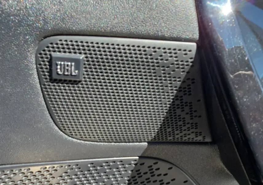Gros plan sur l'enceinte JBL intégrée à la porte côté conducteur d'une Peugeot 208 GTI noire.