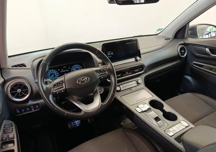 Vue intérieure côté conducteur du tableau de bord et volant cuir noir du Hyundai Kona électrique 2023 avec écran tactile central.