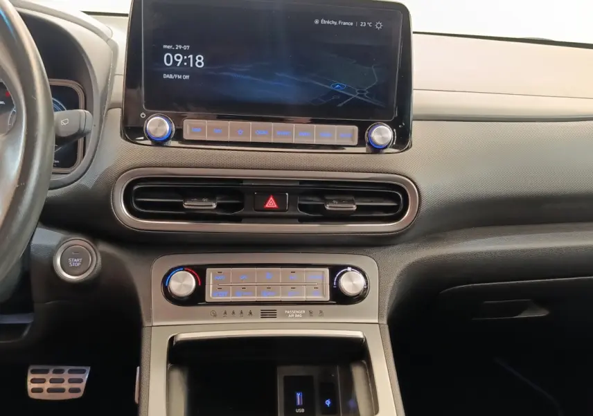 Vue intérieure du tableau de bord du Hyundai Kona électrique 2023 avec écran tactile central et commandes climatisation.