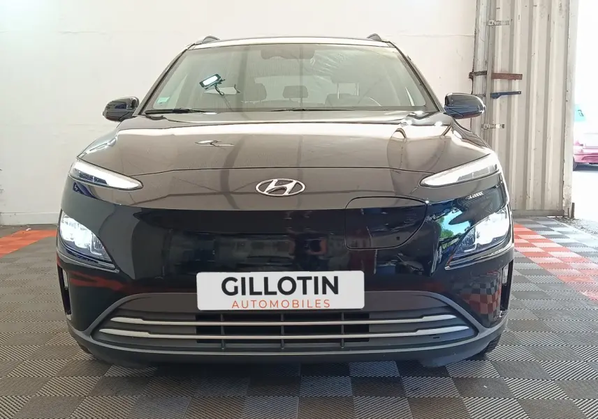Vue de face d'un Hyundai Kona électrique noir 2023 avec phares LED allumés dans un garage.