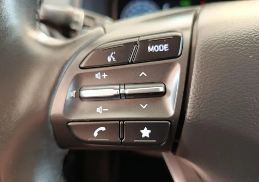 Gros plan sur les commandes du volant côté gauche du Hyundai Kona noir électrique 2023, boutons multifonctions visibles.