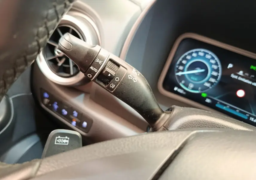 Gros plan sur la commande des feux et clignotants à gauche du volant dans l’habitacle noir du Hyundai Kona électrique 2023.
