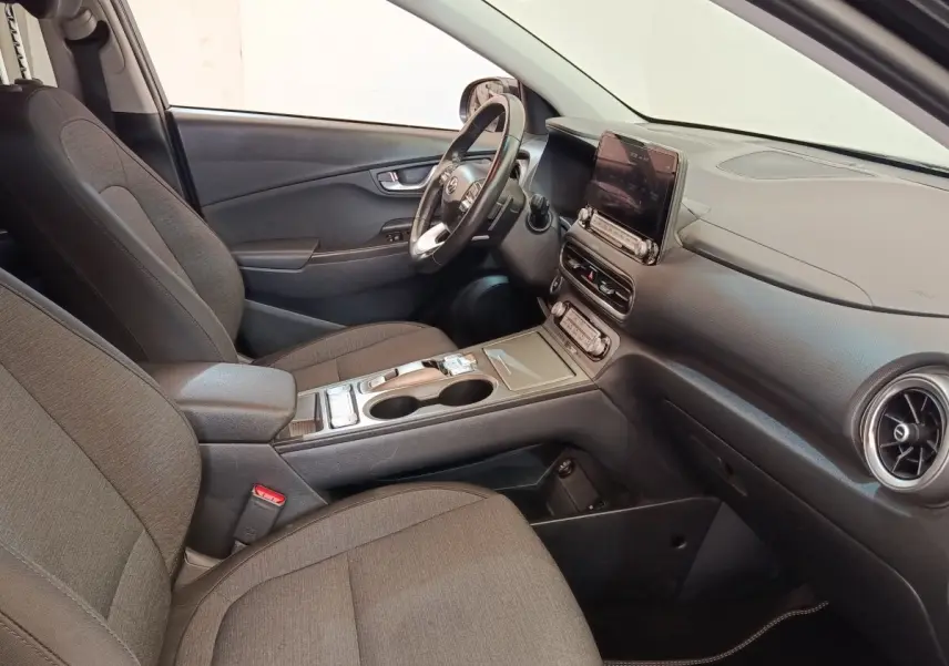 Intérieur avant droit du Hyundai Kona électrique 2023 en tissu gris avec tableau de bord et écran tactile central.
