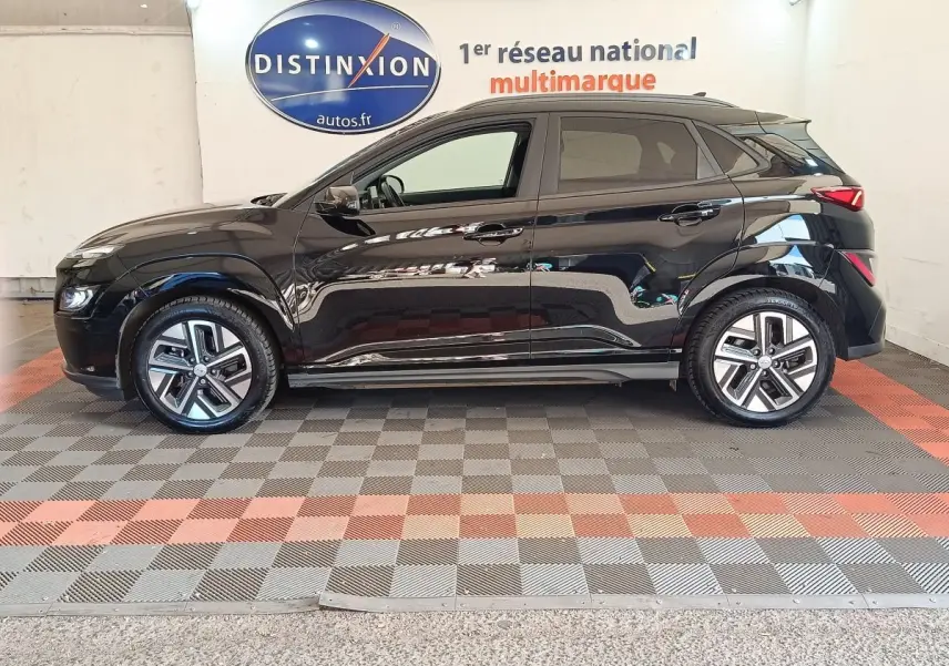 Vue de profil côté gauche d’un Hyundai Kona électrique noir 2023, avec jantes alliage et toit noir contrasté.