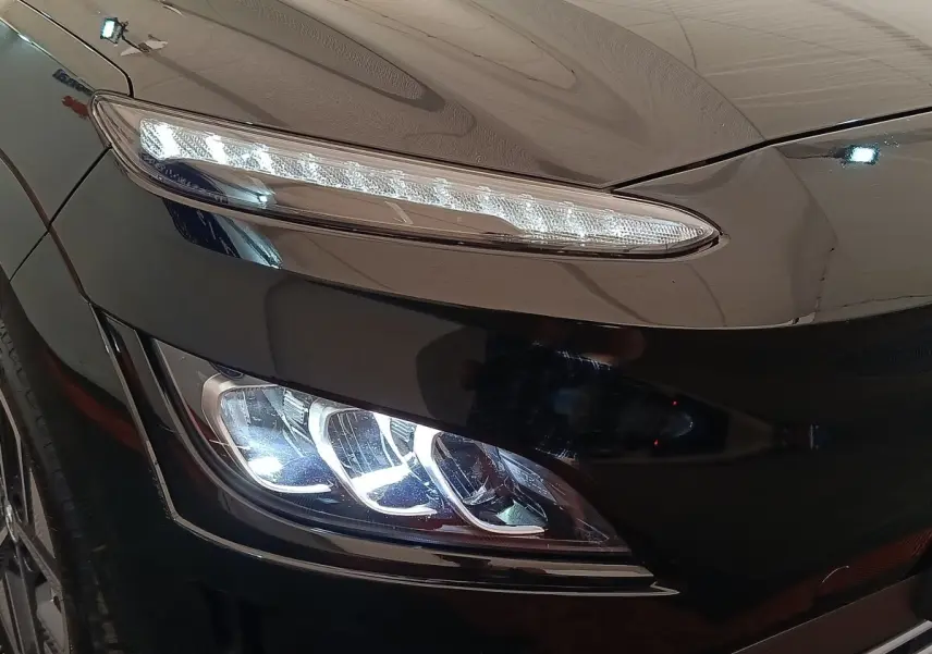 Gros plan sur le phare avant gauche LED du Hyundai Kona noir électrique 2023, mettant en valeur ses lignes modernes.