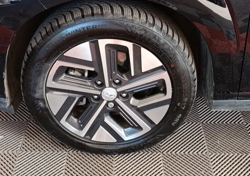 Gros plan sur la roue avant gauche noire d’un Hyundai Kona électrique 2023 avec jante alliage bicolore.
