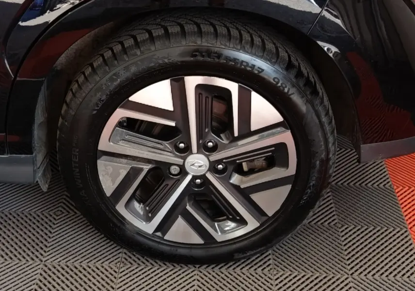 Gros plan sur la roue avant droite noire d’un Hyundai Kona électrique 2023 avec jante alliage bicolore.