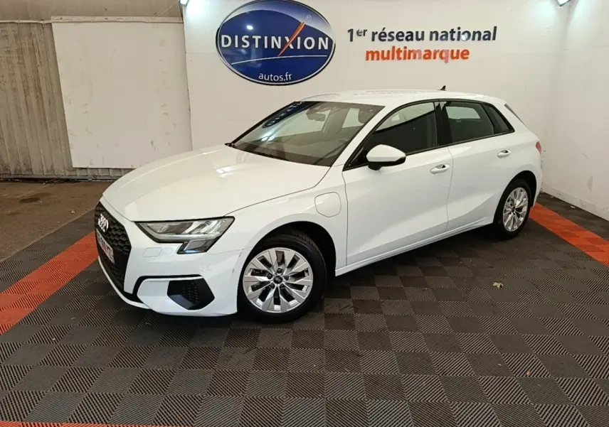 Audi A3 40 TFSI e blanc en 3/4 avant droit, hybride rechargeable, avec jantes alliage et prise de charge visible côté avant gauche.