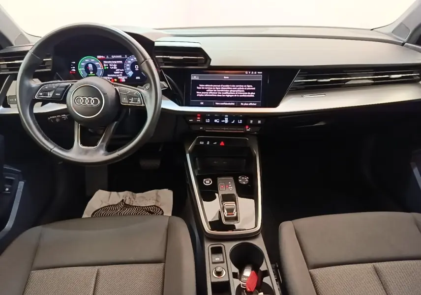 Vue intérieure avant de l'Audi A3 40 TFSI e 2022, tableau de bord noir avec écran tactile et volant cuir multifonctions.