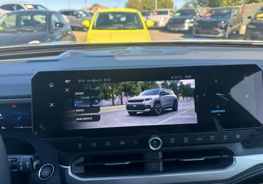 Vue intérieure du tableau de bord du Jeep Compass 2026 avec écran tactile affichant un mode de conduite et une image du véhicule gris.