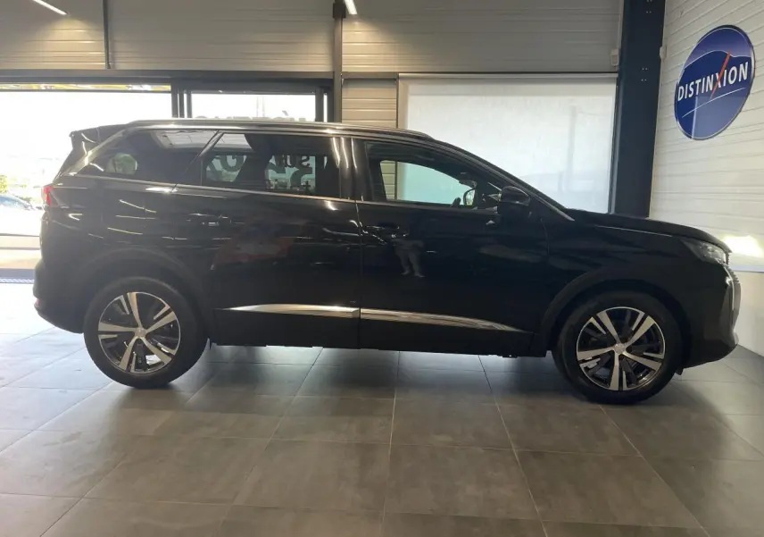 Profil droit du Peugeot 5008 noir métallisé 2024 avec jantes alliage bi-ton et barres de toit profilées en aluminium.
