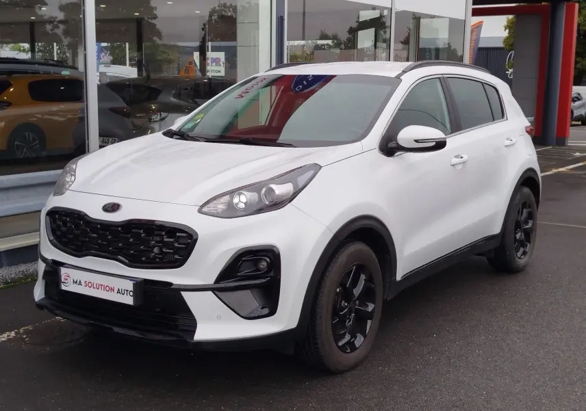 KIA SPORTAGE blanc vu en 3/4 avant droit, avec calandre noire et jantes noires distinctives.