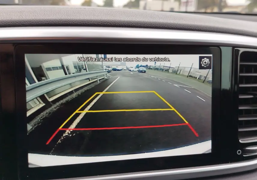 Écran de caméra de recul du Kia Sportage blanc 2022 montrant la route derrière avec repères de stationnement colorés.