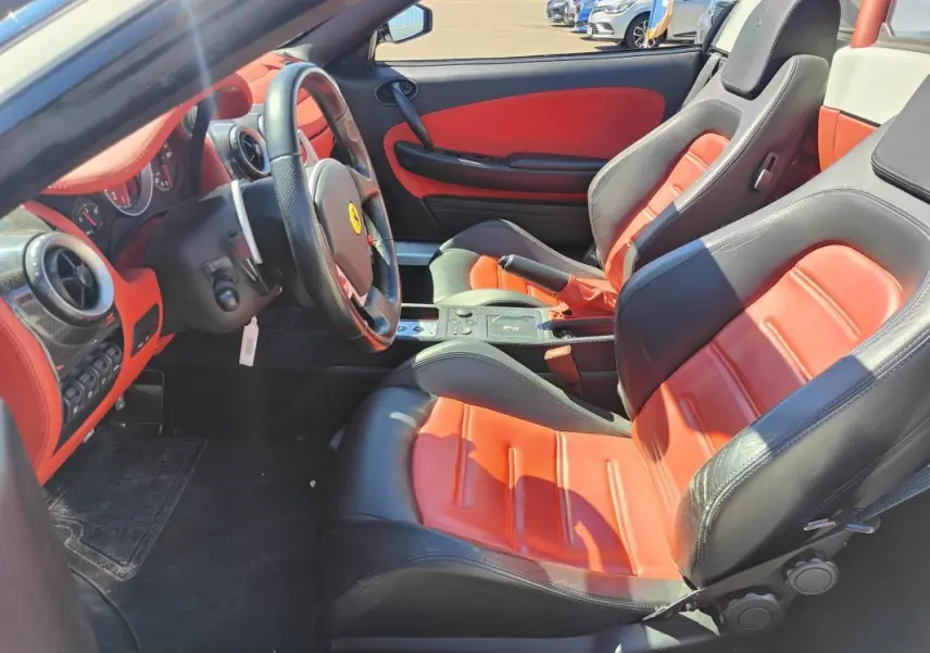 Intérieur de la Ferrari F430 Spider blanc, vue côté conducteur, sièges cuir noir et rouge avec tableau de bord assorti.