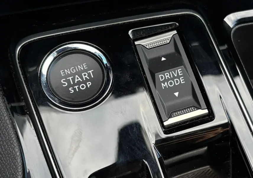 Gros plan sur la console centrale noire brillante du Peugeot 3008 2023, avec bouton Start/Stop et commande Drive Mode.