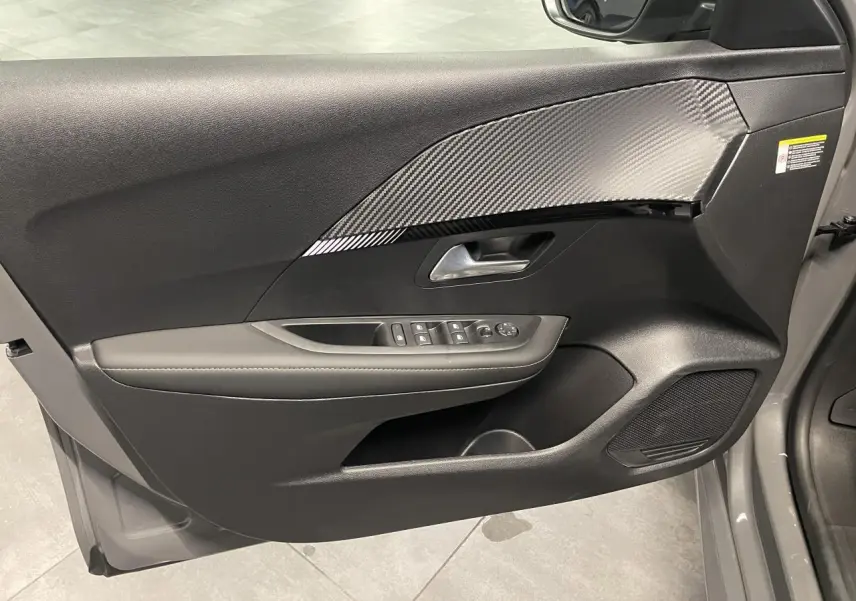 Vue intérieure de la porte avant gauche gris sélénium de la Peugeot 208 Allure avec insert effet carbone et commandes électriques.