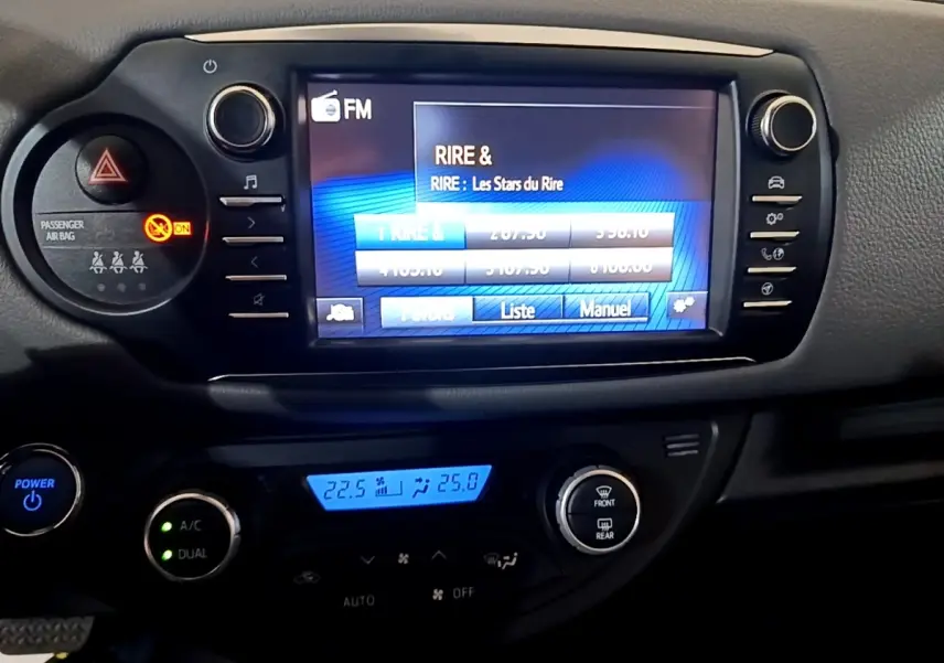 Vue rapprochée du tableau de bord noir de la Toyota Yaris hybride 2019, avec écran tactile et commandes climatisation.