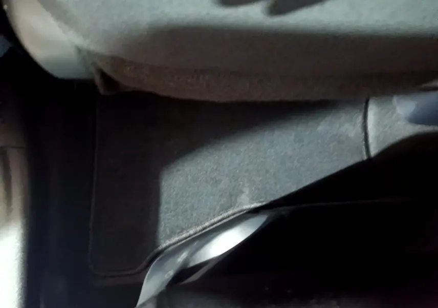 Vue intérieure du plancher arrière avec tapis gris et siège tissu dans une Toyota Yaris blanche hybride 2019.