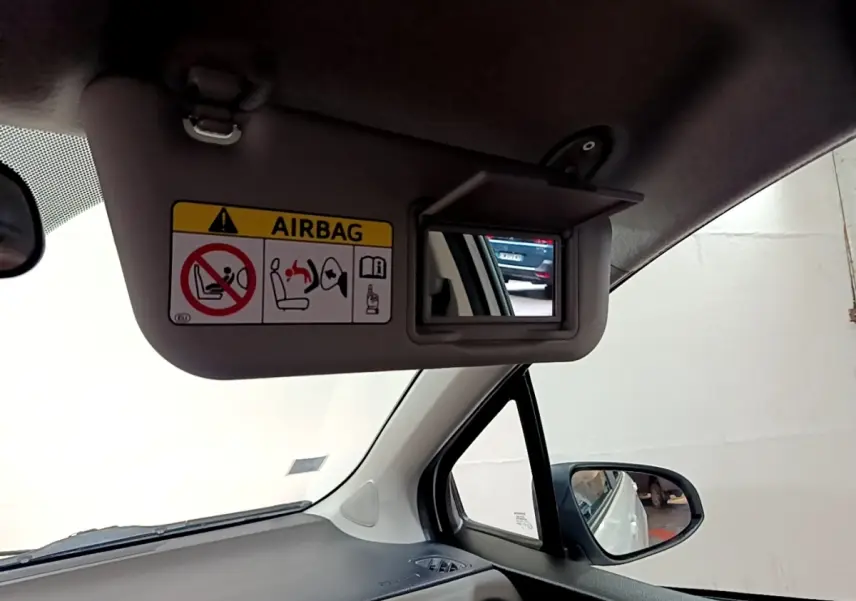 Vue intérieure côté conducteur sur le pare-soleil avec miroir et avertissement airbag de la Toyota Yaris blanche.