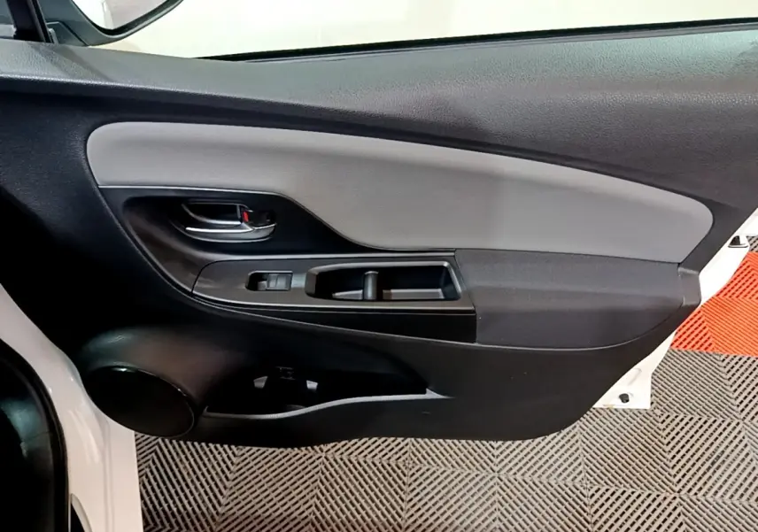 Vue intérieure de la porte avant gauche blanche d'une Toyota Yaris 2019, avec commandes de fenêtre et poignée noire.