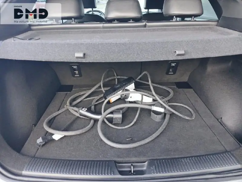 Coffre ouvert du MG4 EV 204ch 2023, vue de l'arrière, avec câble de recharge électrique visible sur le tapis noir.