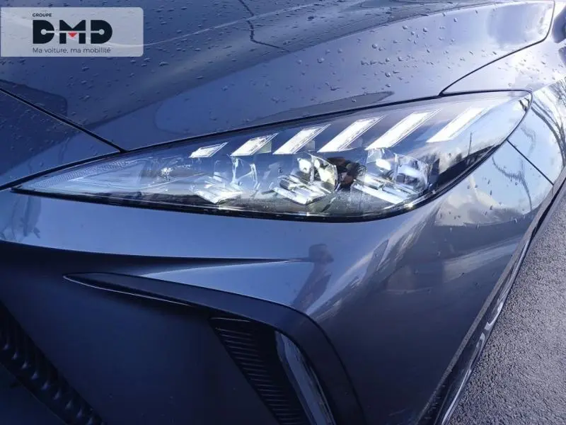 Gros plan sur le phare avant droit du MG4 EV 204ch 2023 en Andes Grey métallisé avec gouttes de pluie visibles.