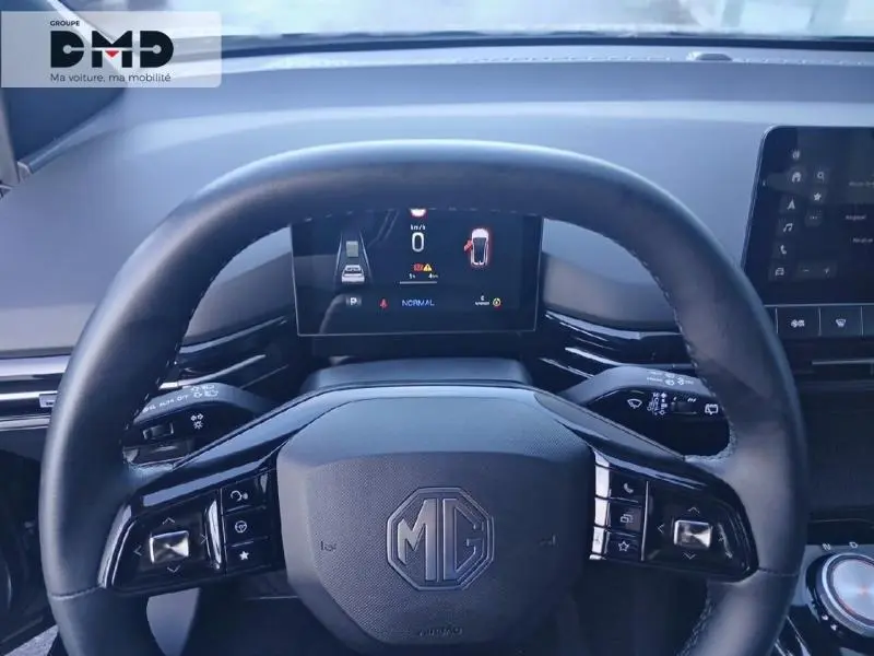 Vue rapprochée du volant noir du MG4 EV 2023 avec tableau de bord numérique et logo MG au centre.