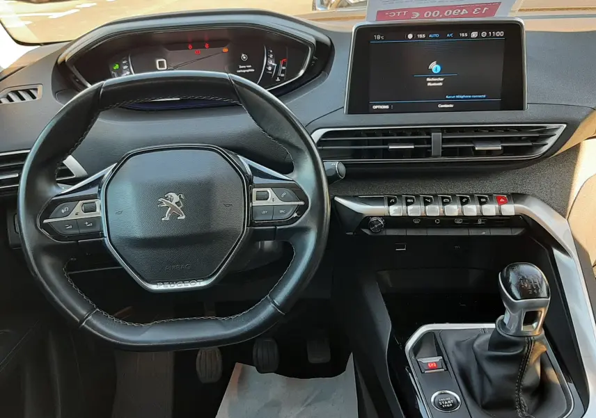 Vue intérieure du tableau de bord et volant du Peugeot 3008 noir, avec écran tactile et levier de vitesse manuel visible.