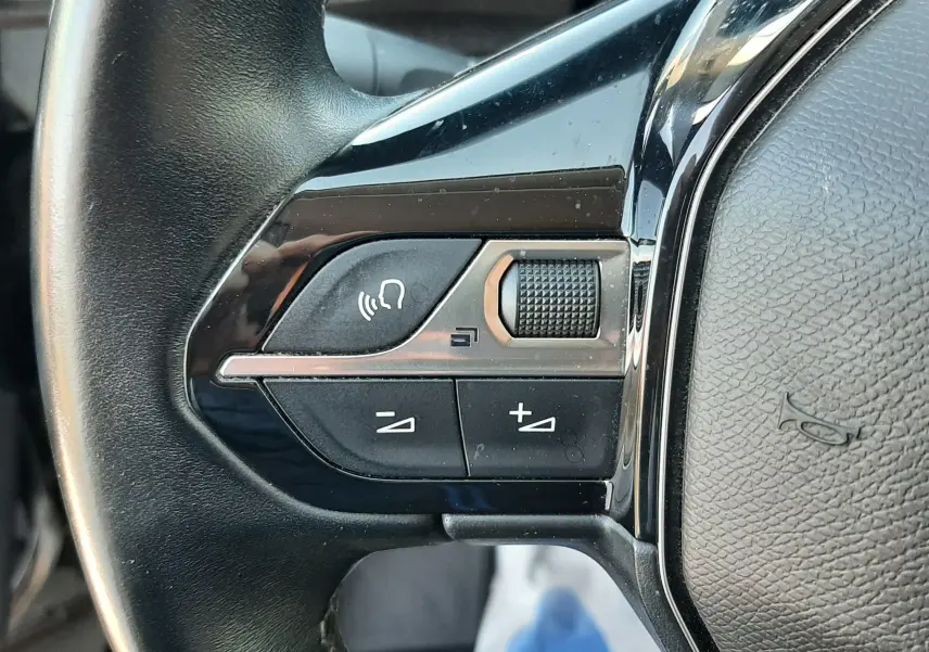 Gros plan sur les commandes gauche du volant noir du Peugeot 3008 2019, avec boutons de volume et commande vocale.