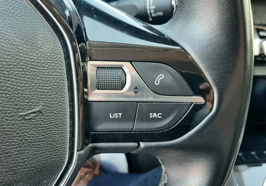 Gros plan sur les commandes gauche du volant noir du Peugeot 3008 2019, avec boutons LIST, SRC et téléphone.