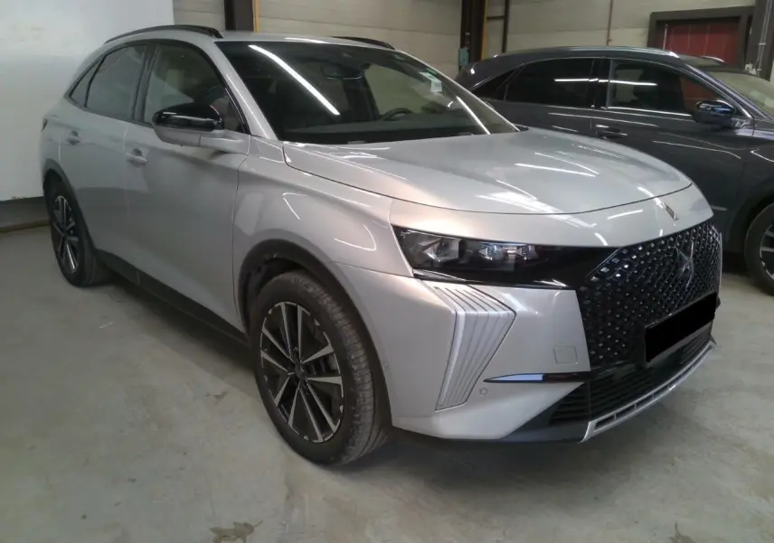 DS7 2025 Cristal Pearl en 3/4 avant droit, avec calandre noire distinctive et jantes alliage 19 pouces.