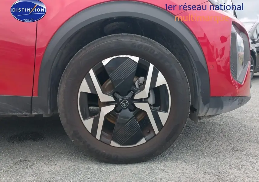 Gros plan sur la roue avant gauche rouge elixir d’un Peugeot 2008 1.2 100 allure avec jante alu distinctive.