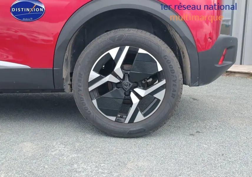 Gros plan sur la roue arrière droite du Peugeot 2008 rouge elixir avec jante alu au design géométrique.