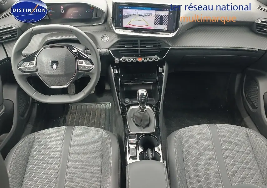 Vue intérieure avant du Peugeot 2008 1.2 100 allure avec tableau de bord numérique et boîte manuelle, sièges tissu gris.